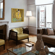 Living room with a painting of 'The Kiss' by Gustav Klimt, a lamp, and decorative pineapple on a coffee table.